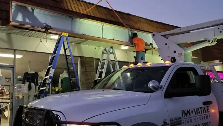 nnovative Sign Systems crew installing a 20-foot cabinet at a retail storefront in San Marcos, CA during evening hours, wearing high-visibility gear