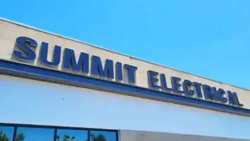 Dark dimensional letters spelling "SUMMIT ELECTRICAL" mounted on a light-colored commercial building facade under a clear blue sky.