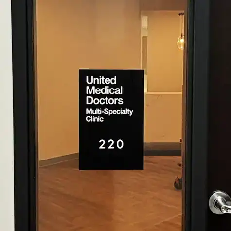 ADA-compliant room identification placard installed on interior glass window.