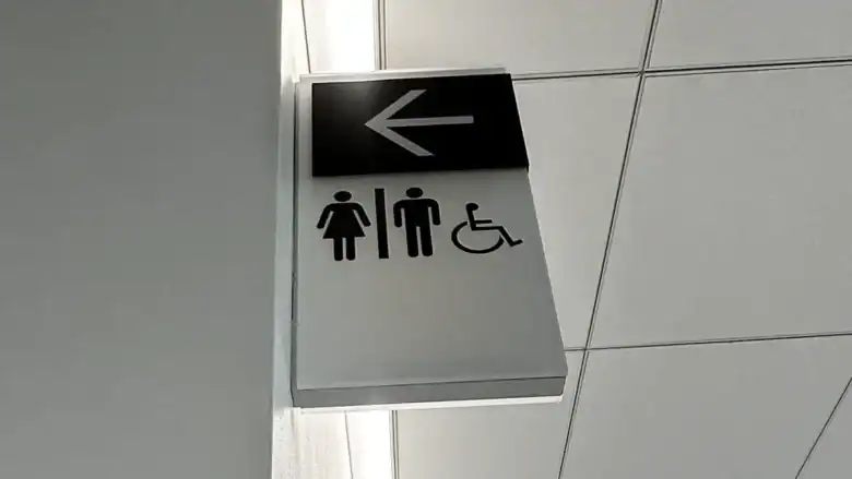 Toilet, wheelchair accessible, and directional sign in a modern building.