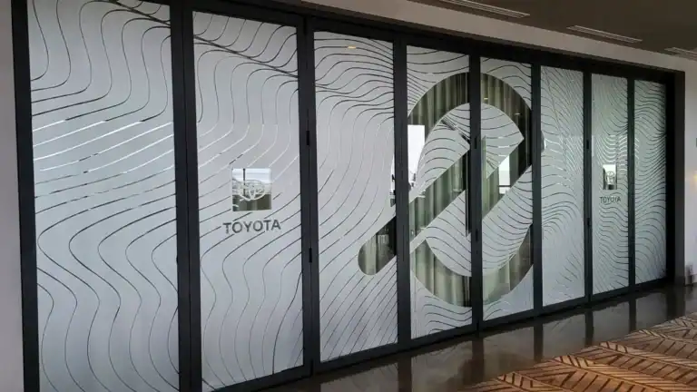 Custom frosted glass vinyl film installed on a wall of folding glass doors for a Toyota/Toyoda event in Encinitas, featuring a large abstract wave pattern and corporate logos.