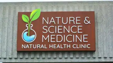 "Nature & Science Medicine" Illuminated Push-Thru Building Sign Cabinet in Encinitas, CA Exterior routed dimensional sign for "NATURE & SCIENCE MEDICINE, NATURAL HEALTH CLINIC" featuring a green sprout in a beaker logo, mounted on a textured building in Encinitas.