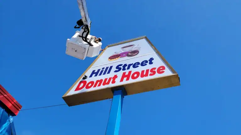 Pylon sign repair for Hill Street Donut House in Oceanside, CA, showing a bucket truck service.