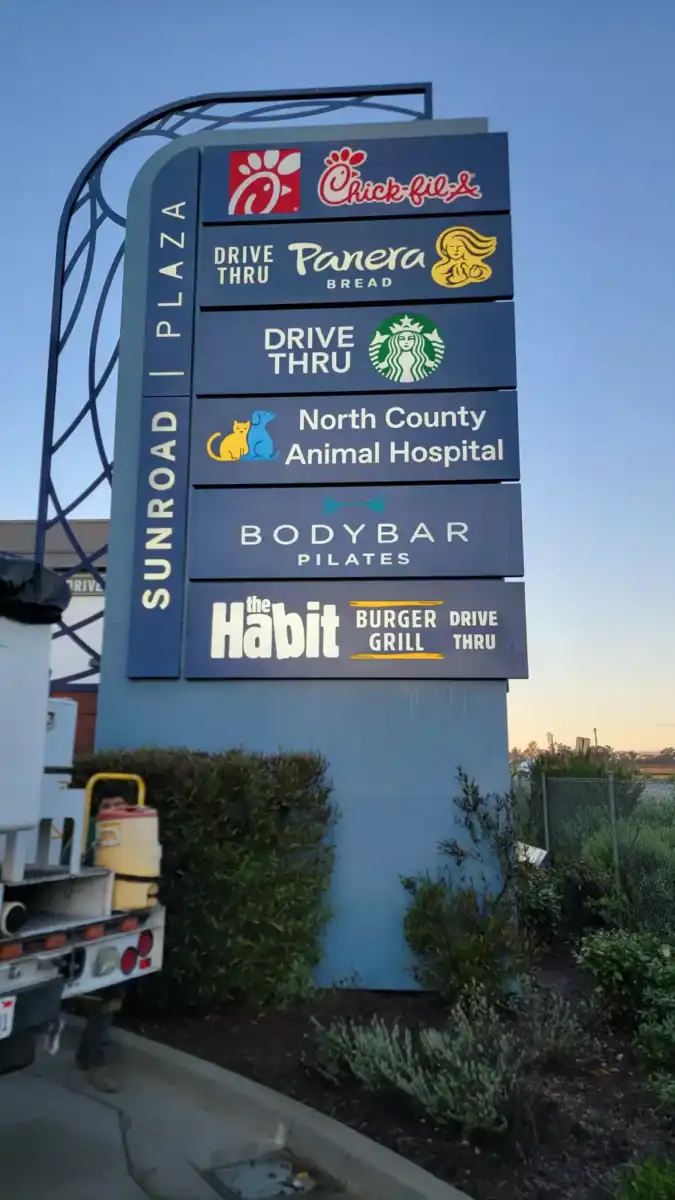 Colorful outdoor business directory sign with illuminated digital displays, listing various local restaurants, cafes, and services.