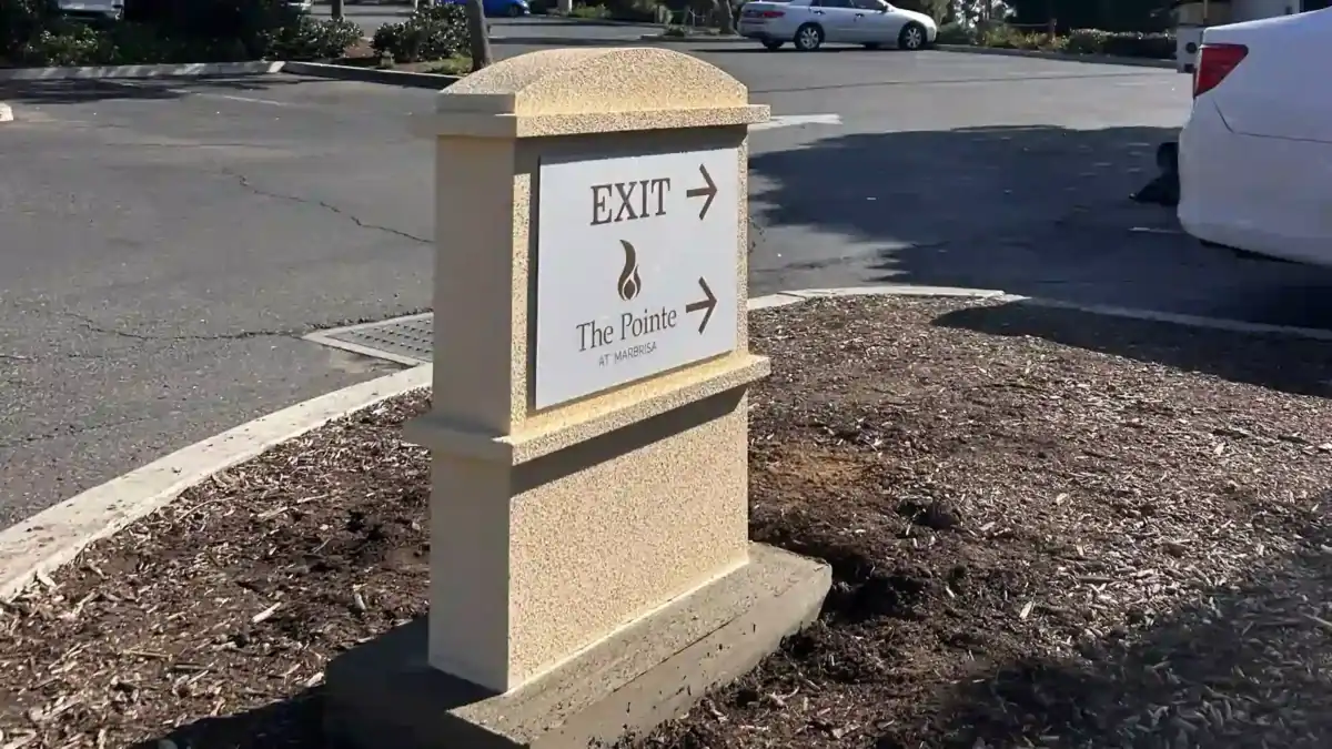 Side view of a textured aluminum monument sign mow strip base and panel installation.